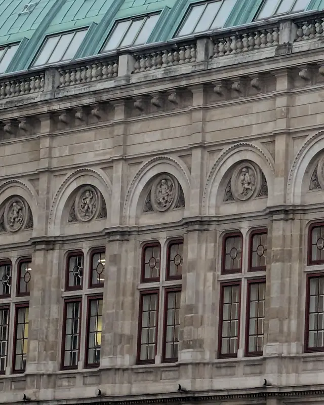 Finestre ad arco e medaglioni in pietra sulla facciata dell'Opera di Stato di Vienna