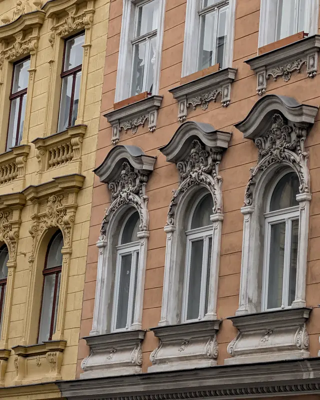 Facciate gialle e rosa con finestre decorate, una accanto all'altra lungo una strada di Vienna
