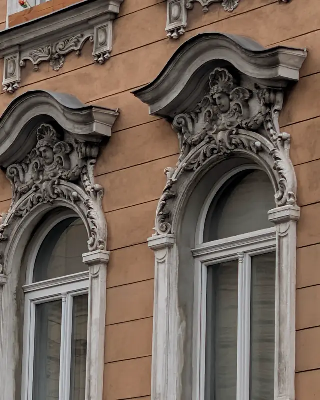 Cornici in stucco sopra le finestre di una facciata rosa a Vienna